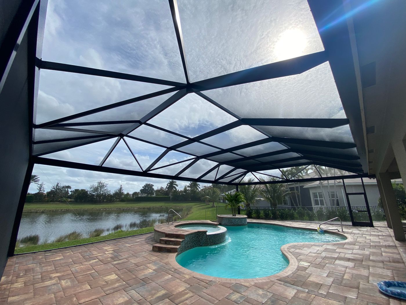 Backyard pool overlooking a lake with a premium screen enclosure.
